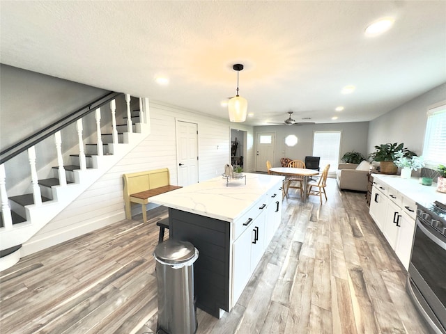 5301 Hemlock Dr, Baytown, TX 77521 - kitchen with light wood-type flooring, a ceiling fan, stainless steel stove, white cabinetry, and a center island