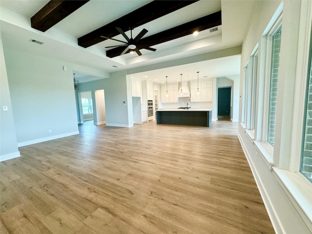 197 Sandpiper Dr, New Waverly, TX 77358 - unfurnished living room with ceiling fan, beam ceiling, light wood-style floors, baseboards, and a sink