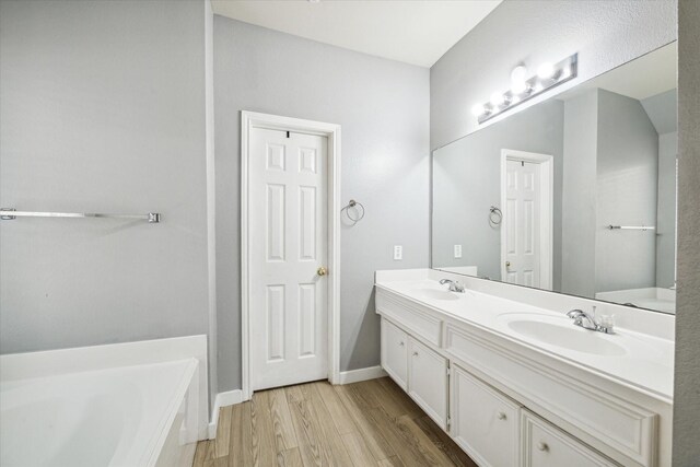 28519 Peper Hollow Ln, Spring, TX 77386 - bathroom with double vanity, wood finished floors, a bath, and baseboards