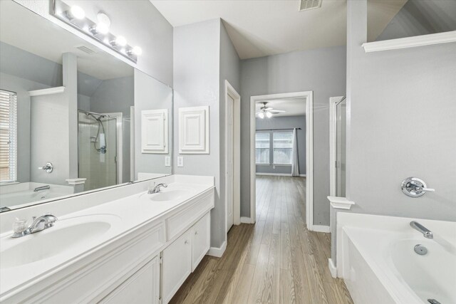 28519 Peper Hollow Ln, Spring, TX 77386 - bathroom featuring a bath, a shower stall, double vanity, wood finished floors, and baseboards