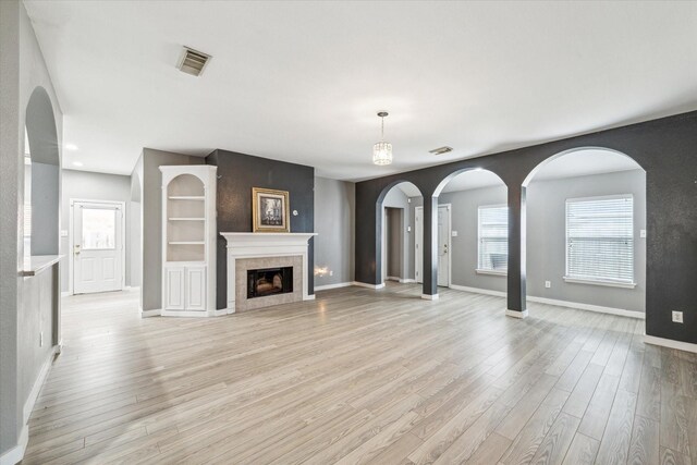 28519 Peper Hollow Ln, Spring, TX 77386 - unfurnished living room featuring light wood-style floors, arched walkways, plenty of natural light, and baseboards