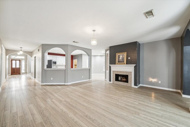 28519 Peper Hollow Ln, Spring, TX 77386 - unfurnished living room with light wood finished floors, baseboards, arched walkways, and a tiled fireplace