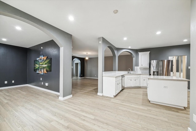 28519 Peper Hollow Ln, Spring, TX 77386 - kitchen with appliances with stainless steel finishes, open floor plan, light wood-style flooring, a sink, and arched walkways