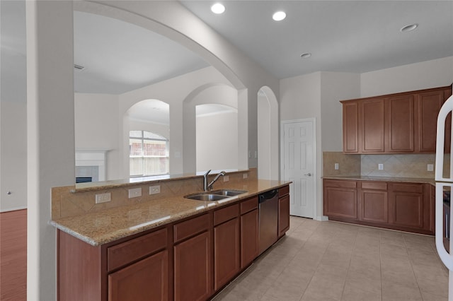 13406 Georgia Hollow Ct, Rosharon, TX 77583 - kitchen with a sink, tasteful backsplash, light stone countertops, a fireplace, and light tile patterned floors