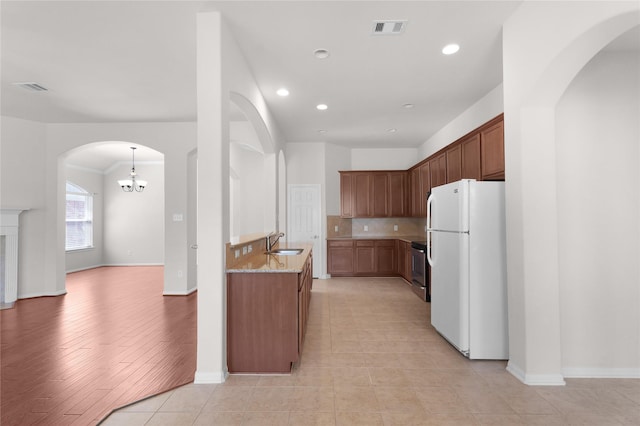 13406 Georgia Hollow Ct, Rosharon, TX 77583 - kitchen with freestanding refrigerator, a sink, arched walkways, recessed lighting, and decorative backsplash