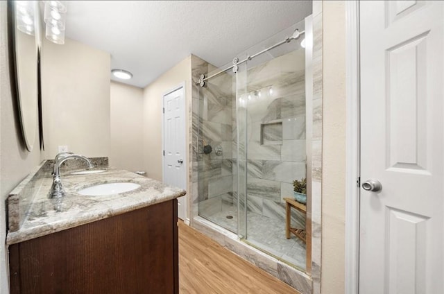 317 Green Isle Ave, Dickinson, TX 77539 - bathroom with double vanity, a shower stall, wood finished floors, and a textured ceiling
