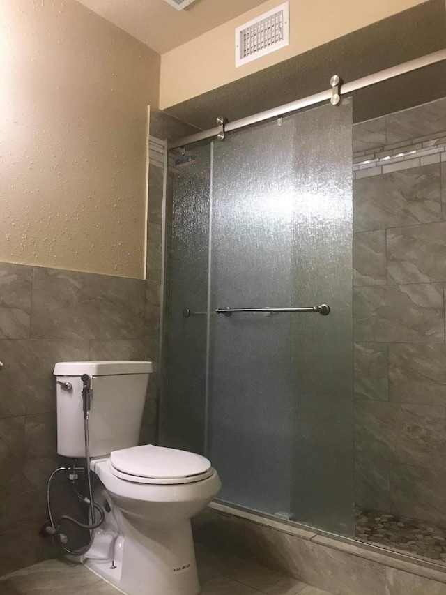 9350 Country Creek Dr Unit 1, Houston, TX 77036 - full bath featuring tile walls, a shower stall, toilet, and a textured wall