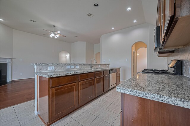 3934 Medici Ct, Missouri City, TX 77459 - kitchen with arched walkways, a ceiling fan, appliances with stainless steel finishes, a sink, and light tile patterned floors