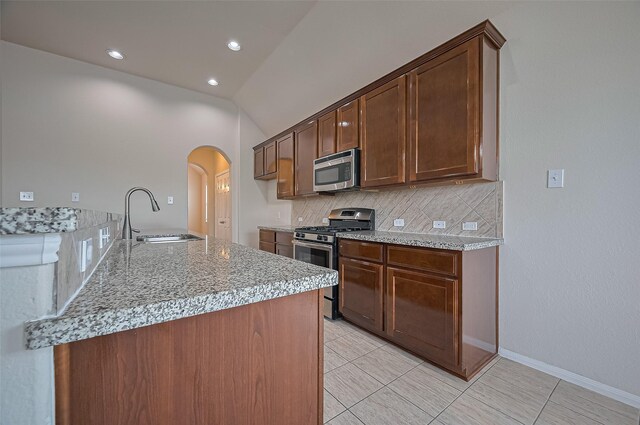 3934 Medici Ct, Missouri City, TX 77459 - kitchen featuring stainless steel appliances, a sink, decorative backsplash, arched walkways, and light tile patterned floors