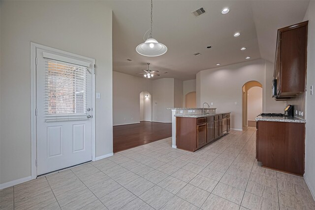 3934 Medici Ct, Missouri City, TX 77459 - kitchen featuring arched walkways, a ceiling fan, light stone countertops, open floor plan, and recessed lighting