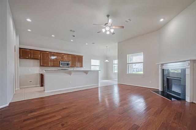 3934 Medici Ct, Missouri City, TX 77459 - unfurnished living room featuring light wood-type flooring, ceiling fan, a fireplace, recessed lighting, and baseboards