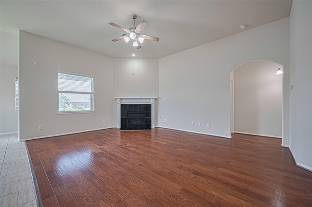 3934 Medici Ct, Missouri City, TX 77459 - unfurnished living room with a ceiling fan, hardwood / wood-style flooring, arched walkways, and a fireplace