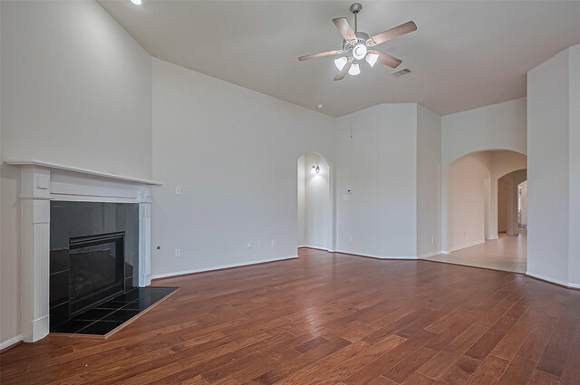 3934 Medici Ct, Missouri City, TX 77459 - unfurnished living room with arched walkways, ceiling fan, wood finished floors, and a tile fireplace