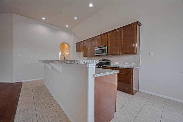 3934 Medici Ct, Missouri City, TX 77459 - kitchen with appliances with stainless steel finishes, arched walkways, lofted ceiling, tasteful backsplash, and recessed lighting