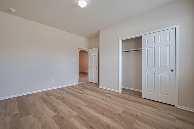 3934 Medici Ct, Missouri City, TX 77459 - unfurnished bedroom featuring light wood finished floors, baseboards, arched walkways, and a closet