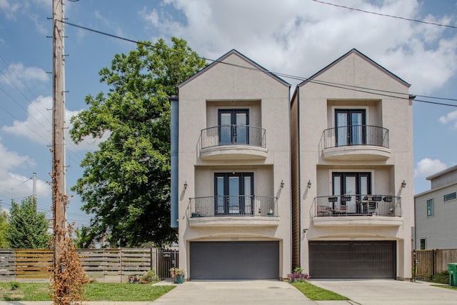 1205 Sampson St, Houston, TX 77003 - townhome / multi-family property featuring french doors, a balcony, stucco siding, an attached garage, and driveway