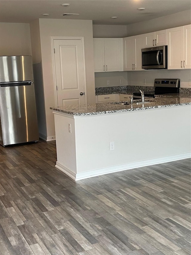 15508 Taylorcrest Dr, Conroe, TX 77306 - kitchen featuring stainless steel appliances, dark stone countertops, white cabinets, dark wood-type flooring, and recessed lighting