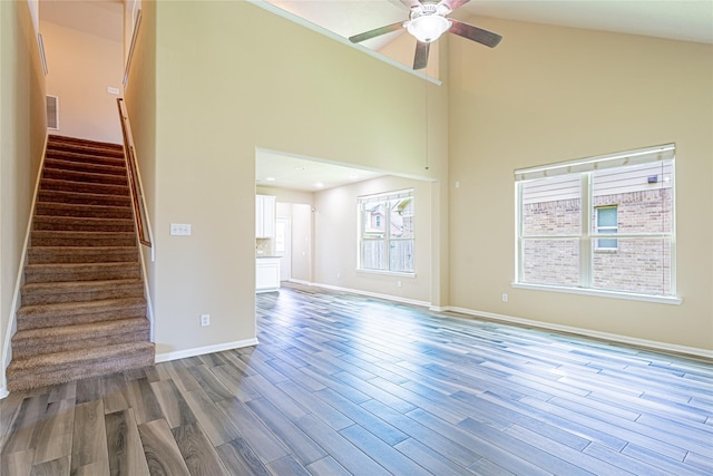 8138 Heartbrook Field Ln, Cypress, TX 77433 - unfurnished living room with wood finished floors, a ceiling fan, stairs, and a towering ceiling