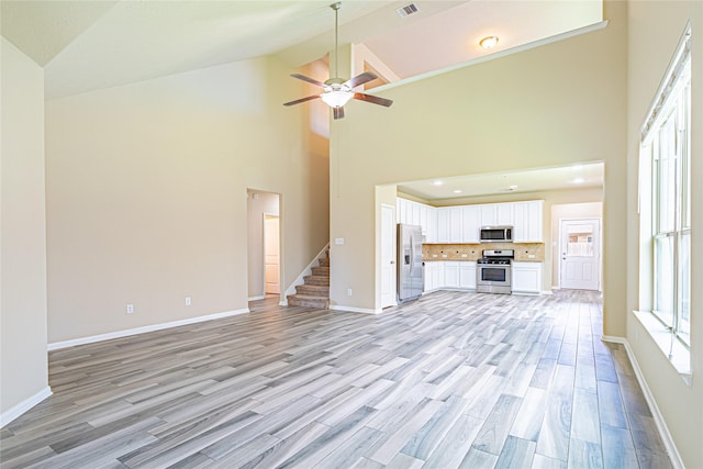 8138 Heartbrook Field Ln, Cypress, TX 77433 - unfurnished living room featuring high vaulted ceiling, light wood-style flooring, a ceiling fan, and stairs
