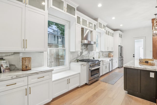 412 Hawthorne St, Houston, TX 77006 - kitchen featuring high quality appliances, wall chimney exhaust hood, tasteful backsplash, white cabinets, and recessed lighting