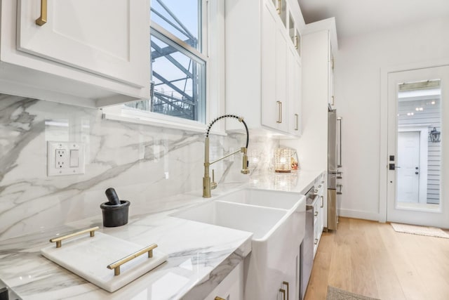 412 Hawthorne St, Houston, TX 77006 - kitchen with a sink, backsplash, white cabinetry, light wood finished floors, and glass insert cabinets