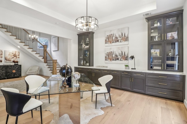 412 Hawthorne St, Houston, TX 77006 - dining room featuring stairs, light wood-style floors, a chandelier, and a raised ceiling