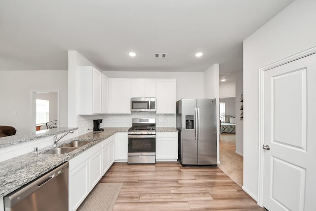 1110 Bending Trail Dr, Tomball, TX 77375 - kitchen with stainless steel appliances, a sink, light stone countertops, white cabinetry, and tasteful backsplash