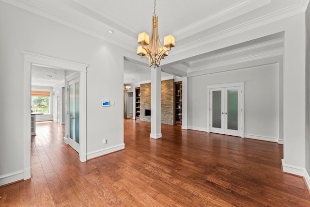 44 Vinebrook Rd, The Woodlands, TX 77380 - unfurnished living room with a chandelier, hardwood / wood-style floors, crown molding, baseboards, and french doors