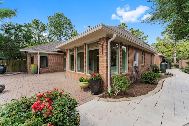 44 Vinebrook Rd, The Woodlands, TX 77380 - view of property exterior with brick siding, a patio, and roof with shingles