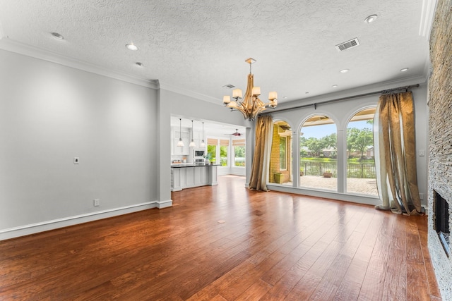 44 Vinebrook Rd, The Woodlands, TX 77380 - unfurnished living room with a chandelier, wood-type flooring, a fireplace, ornamental molding, and a textured ceiling