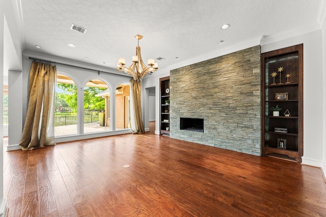 44 Vinebrook Rd, The Woodlands, TX 77380 - unfurnished living room featuring a chandelier, a textured ceiling, wood finished floors, a stone fireplace, and ornamental molding