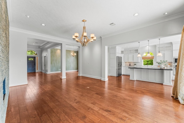44 Vinebrook Rd, The Woodlands, TX 77380 - unfurnished living room featuring a stone fireplace, a chandelier, hardwood / wood-style floors, crown molding, and baseboards