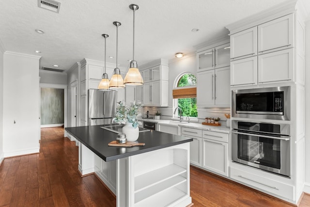 44 Vinebrook Rd, The Woodlands, TX 77380 - kitchen featuring appliances with stainless steel finishes, a sink, crown molding, hanging light fixtures, and an island with sink