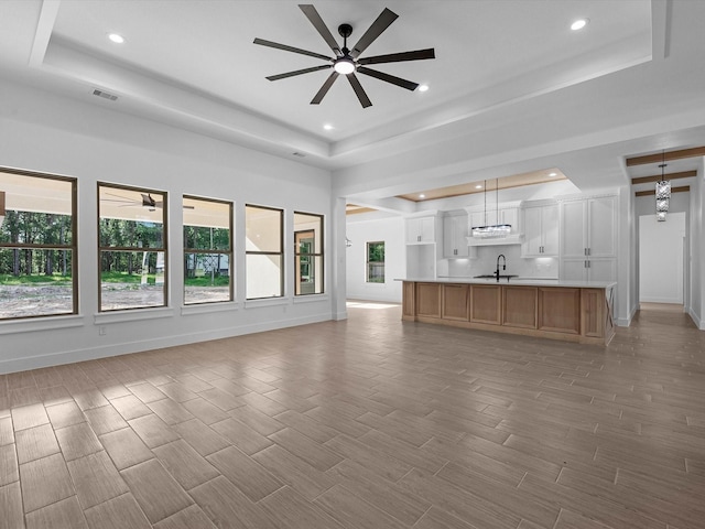 17107 Alara Dr, Splendora, TX 77372 - unfurnished living room featuring a tray ceiling, a ceiling fan, a sink, baseboards, and recessed lighting
