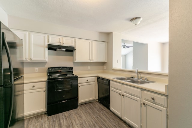 6930 Caddo Lake Ln, Houston, TX 77083 - kitchen featuring black appliances, under cabinet range hood, light countertops, wood finished floors, and white cabinetry