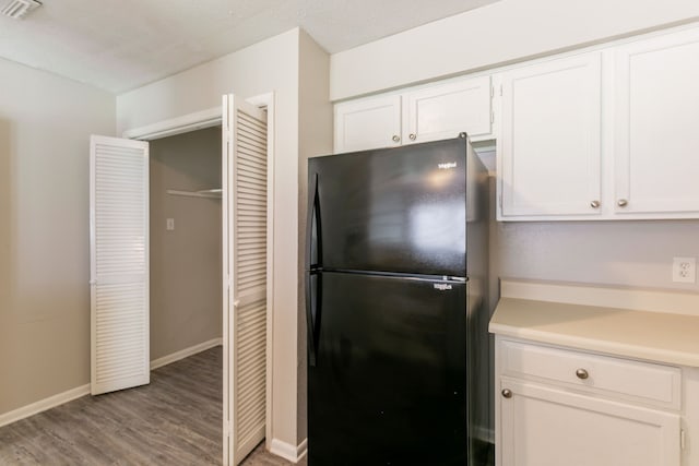6930 Caddo Lake Ln, Houston, TX 77083 - kitchen with freestanding refrigerator, white cabinets, wood finished floors, and light countertops
