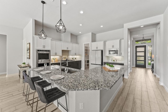 4215 Wooded Isle Way, Fulshear, TX 77441 - kitchen featuring stainless steel appliances, a sink, light wood finished floors, baseboards, and recessed lighting