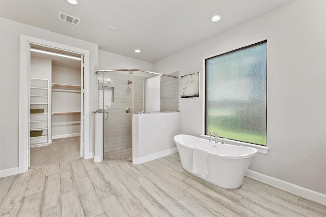 4215 Wooded Isle Way, Fulshear, TX 77441 - bathroom featuring a stall shower, a spacious closet, a freestanding bath, wood finished floors, and recessed lighting