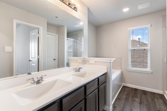 4438 Stephanie Park Ln, Conroe, TX 77304 - full bathroom featuring wood finished floors, double vanity, a shower stall, and a garden tub