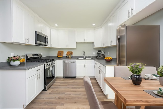 9510 Chesterfield Dr, Houston, TX 77051 - kitchen featuring stainless steel appliances, a sink, dark countertops, white cabinets, and light wood finished floors