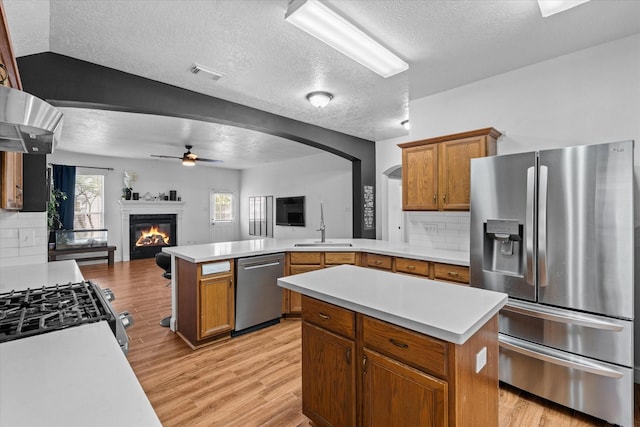 11411 Sugarbush Ridge Ln, Houston, TX 77089 - kitchen featuring stainless steel appliances, a peninsula, open floor plan, a textured ceiling, and light countertops