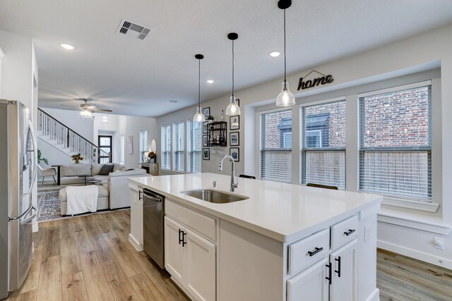 20923 Grand Surprise Ct, Cypress, TX 77433 - kitchen with stainless steel appliances, a sink, light wood-style flooring, open floor plan, and white cabinets