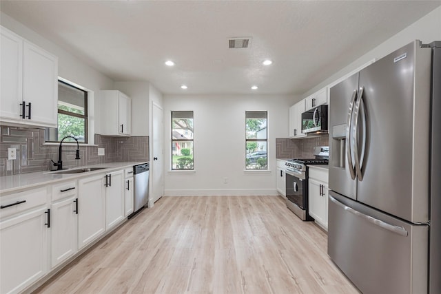 12034 Audubon Hill Ct, Houston, TX 77038 - kitchen with appliances with stainless steel finishes, a sink, light wood-style floors, decorative backsplash, and light countertops