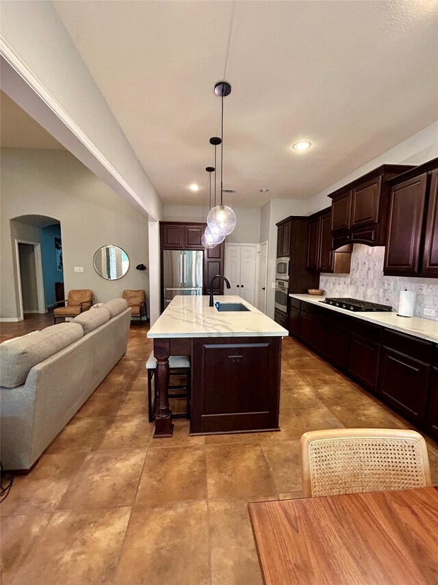 15127 Turquoise Mist Dr, Cypress, TX 77433 - kitchen with arched walkways, appliances with stainless steel finishes, open floor plan, tasteful backsplash, and dark brown cabinets