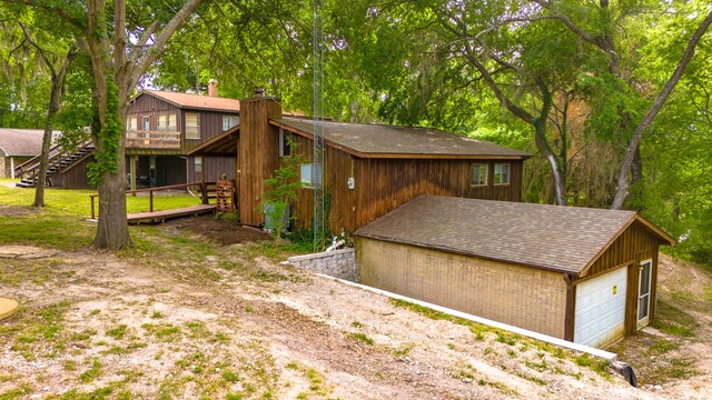 12 Walker Trl, Huntsville, TX 77320 - back of property featuring a detached garage, a wooden deck, stairs, a chimney, and a shingled roof