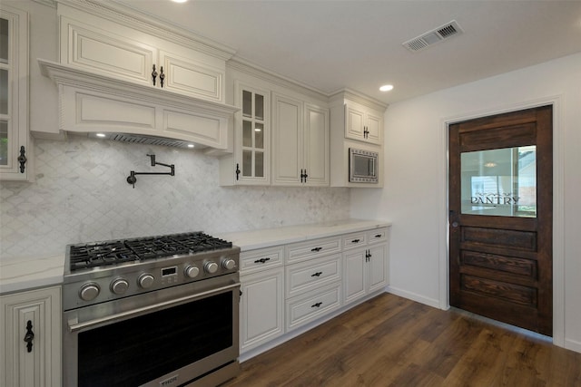 2742 Triway Ln, Houston, TX 77043 - kitchen featuring appliances with stainless steel finishes, glass insert cabinets, decorative backsplash, dark wood-style floors, and light stone counters
