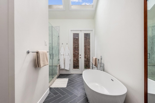9410 Windrush Dr, Spring, TX 77379 - full bath featuring french doors, a freestanding bath, a stall shower, tile patterned flooring, and a skylight