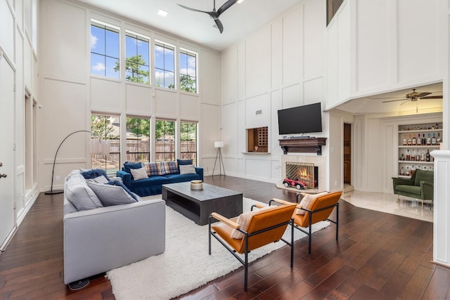 9410 Windrush Dr, Spring, TX 77379 - living room featuring ceiling fan, a towering ceiling, built in shelves, a decorative wall, and dark wood-type flooring