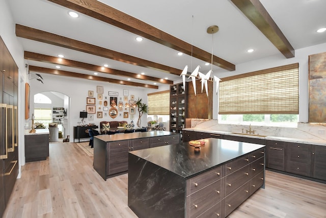 7153 Fm 1458th Rd, Sealy, TX 77474 - kitchen with a center island, beamed ceiling, a sink, arched walkways, and light wood-style flooring