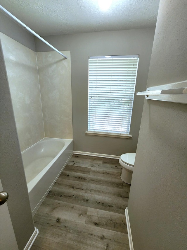2623 Sable Ridge Ln, Katy, TX 77494 - bathroom with toilet, wood finished floors, tub / shower combination, baseboards, and a textured ceiling
